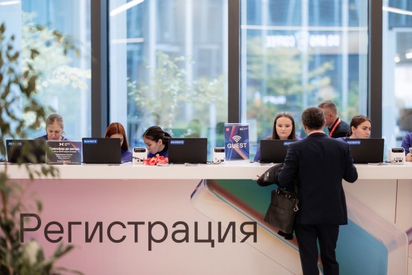 Стойка регистрации участников у панорамного окна, гости подходят за бейджами