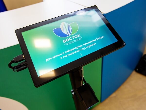 Сенсорный терминал форума «Восток» с инструкцией приложить бейдж к считывателю снизу экрана