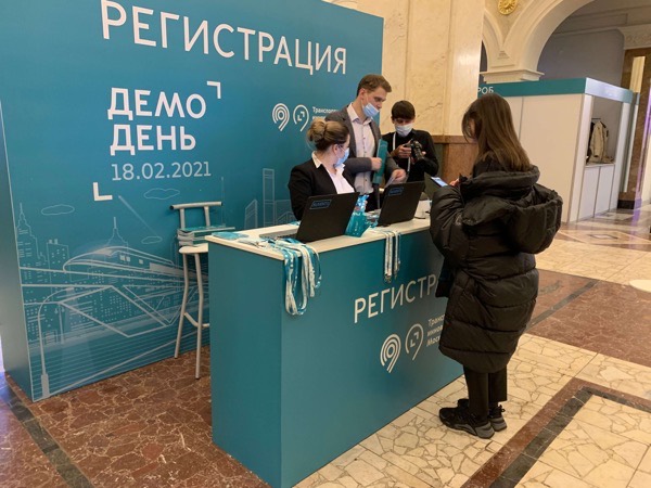 Стойка регистрации «Демо дня» инновационного форума Москвы, сотрудники в масках оформляют гостью