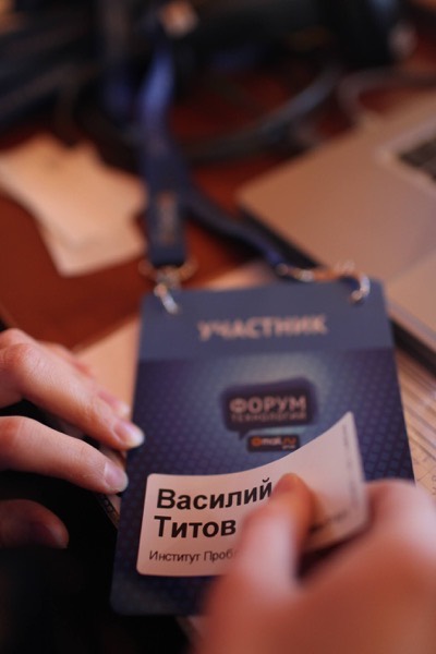 Крупный план бейджа участника форума с именем «Василий Титов» на синем шнурке