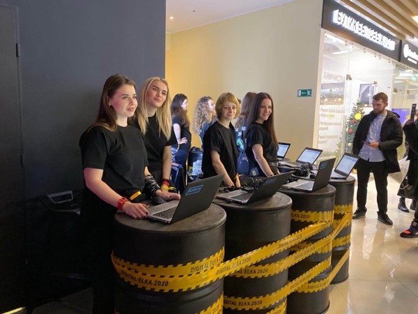 Четыре сотрудницы в чёрном стоят за ноутбуками на бочках с лентой «Digital Elka 2020»