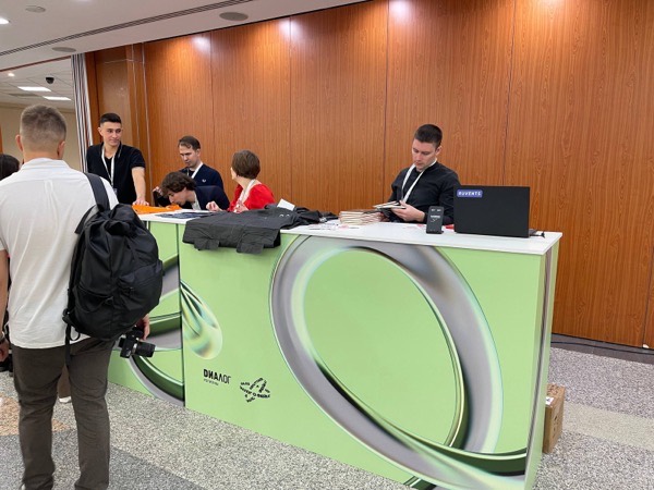 Точка выдачи с ноутбуком и принтером на стойке в конференц-зале, к ней подходят участники