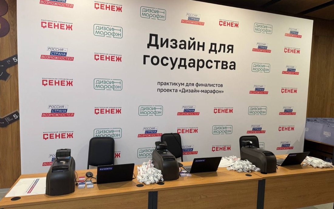 Стойка регистрации у пресс-волла практикума «Дизайн для государства» с принтерами бейджей и ноутбуками