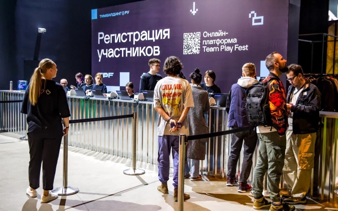 Очередь участников у длинной линии стоек регистрации под вывеской «Регистрация участников»